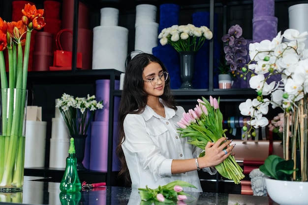 Foto eine junge floristin kümmert sich um blumen in einem gemütlichen blumenladen und sammelt blumensträuße floristik und herstellung von eimern in einem blumenladen kleines unternehmen