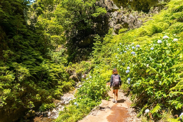 Eine junge Frau auf dem Weg neben dem Wasserfall bei Levada do Caldeirao Verde Queimadas Madeira