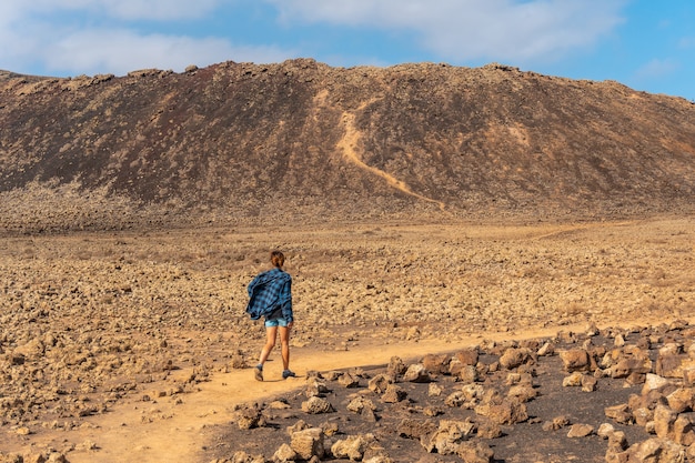 Eine junge Frau auf dem Weg zum Krater des Vulkans Calderon Hondo in der Nähe von Corralejo, Nordküste der Insel Fuerteventura, Kanarische Inseln. Spanien