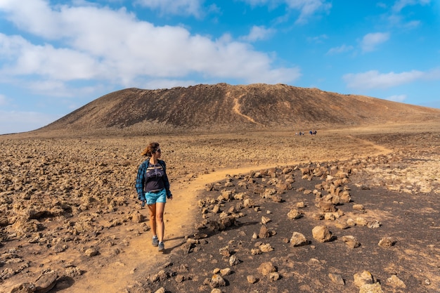 Eine junge Frau auf dem Weg zum Krater des Vulkans Calderon Hondo in der Nähe von Corralejo, Nordküste der Insel Fuerteventura, Kanarische Inseln. Spanien