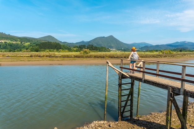 Eine junge Frau auf den Holzpfeilern der Urdaibai-Sümpfe, einem Biosphärenreservat Bizkaias neben Mundaka. Baskenland