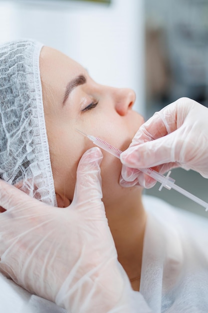 Eine junge Frau bei einem Termin mit einer Kosmetikerin Beauty-Injektionen für das Gesicht Behandlungsablauf bei einem Dermatologen