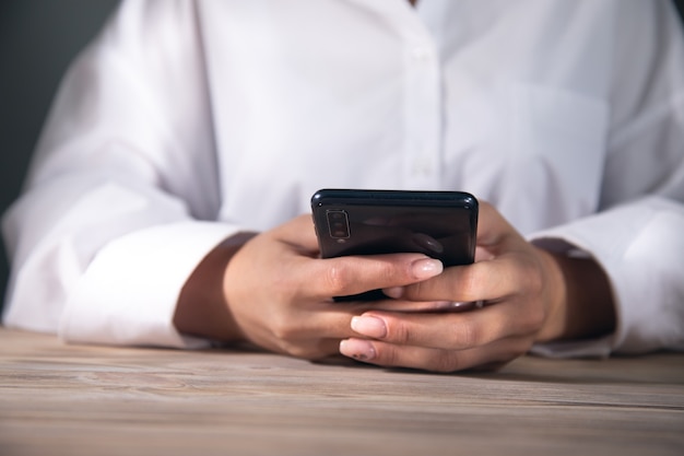 Eine junge Frau benutzt ihr Smartphone an einem Tisch