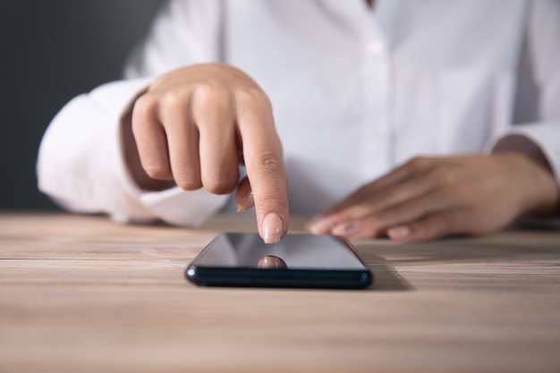 Foto eine junge frau benutzt ihr smartphone an einem tisch