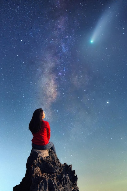 Foto eine junge frau beobachtet die schönheit der milchstraße und einen meteorit auf den felsen