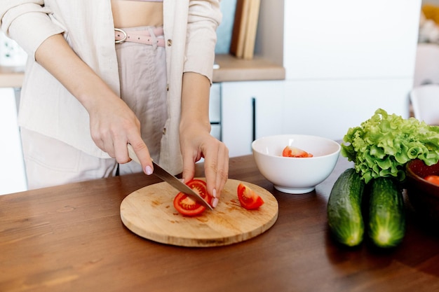 Eine junge Frau bereitet zu Hause Gemüsesalat zu Vegane Küche