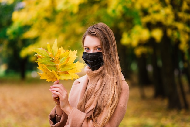 Eine junge Frau, die beim Gehen im Park vor dem Koronavirus schützt