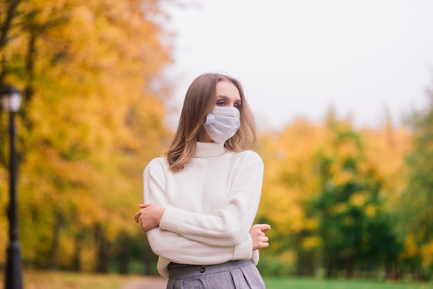 Eine junge Frau, die beim Gehen im Park vor dem Koronavirus schützt