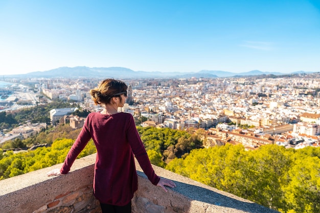 Eine junge Frau, die die schöne Stadt von der Mauer der Burg Gibralfaro in der Stadt Malaga, Andalusien, bewundert. Spanien