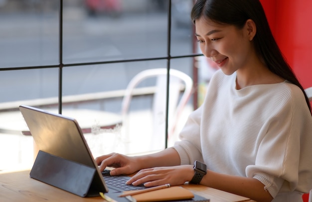 Eine junge Frau, die einen Laptop mit einem lächelnden Ausdruck benutzt, sie Video online mit Freunden