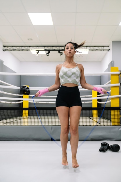 Eine junge Frau, die in der Turnhalle für ihr Boxtraining Seil springt