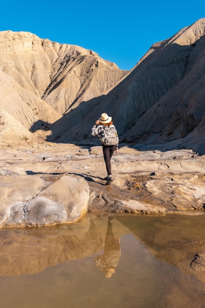 Eine junge Frau, die in der Wüste auf einer Wanderung am Travertino-Wasserfall und auf der Rambla de Otero in der Wüste von Tabernas, Provinz AlmerÃƒÃ‚Âa, Andalusien, am Wasser entlang geht