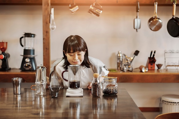 Eine junge Frau, die in einem ruhig beleuchteten Raum Kaffee mit einem Handtropf brüht