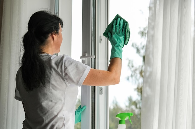 Eine junge Frau, die zu Hause Fenster putzt, allgemeines Reinigungskonzept