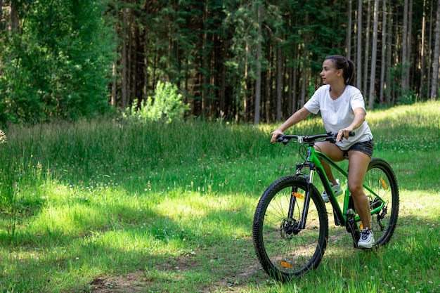 Eine junge Frau fährt Fahrrad in einer bergigen Gegend im Wald