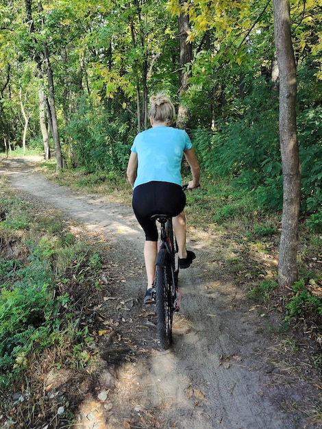 Eine junge Frau fährt im Park mit dem Fahrrad Aktiver Erholung in der Natur Rückwand