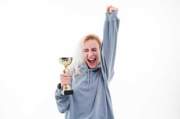 Eine junge Frau freut sich über den Gewinn des Wettbewerbs Modell mit dem Pokal des Gewinners des Wettbewerbs auf weißem Hintergrund