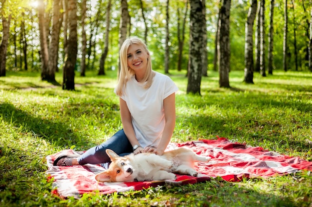 Eine junge Frau geht mit ihrem Hund in einem Sommerpark spazieren