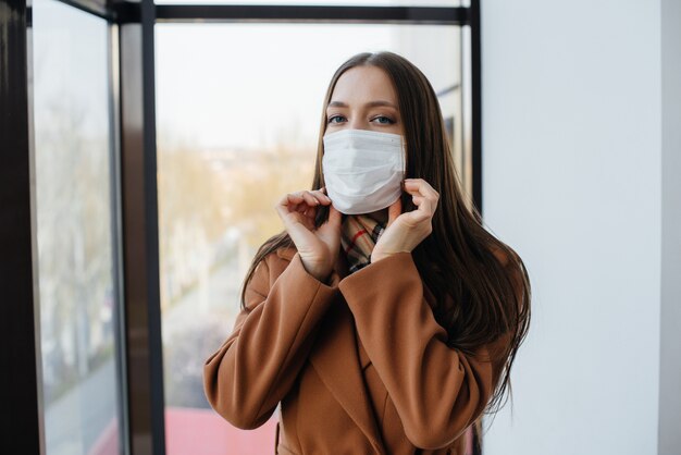 Eine junge Frau geht während der Pandemie und des Coronovirus in einer Maske spazieren. Quarantäne