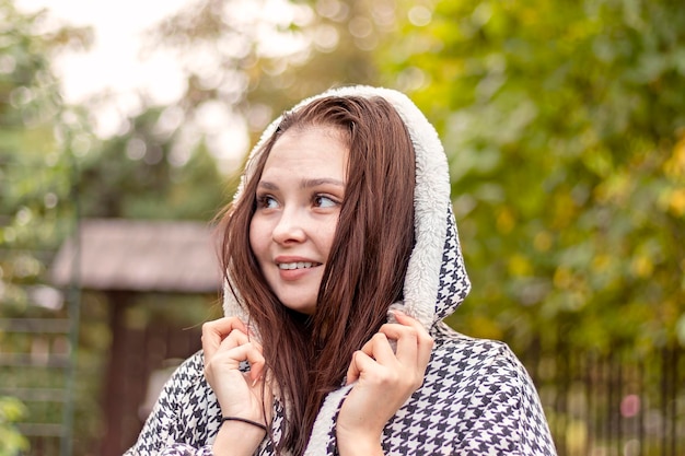 Eine junge Frau genießt einen Spaziergang in einem Herbstpark in einer stylischen Kapuzenjacke