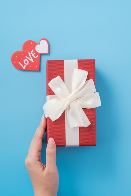 Eine junge Frau gibt ein Geschenk mit herzförmigem Etikett und Textliebe. Valentinstag Konzept
