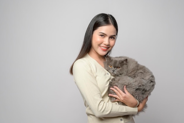 Eine junge Frau hält eine schöne Katze, die mit einer Katze im Studio auf weißem Hintergrund spielt