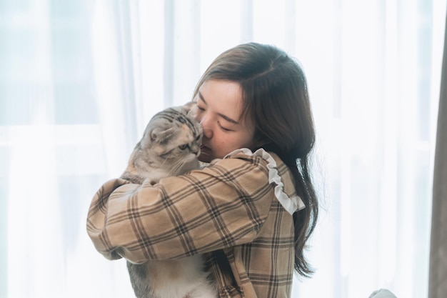 Eine junge Frau hält eine schöne Katze, die mit einer Katze spielt