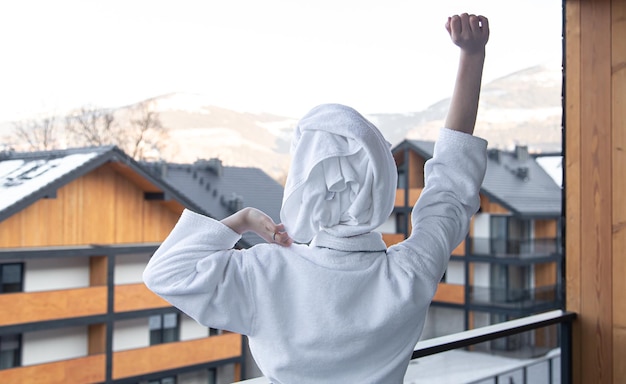 Eine junge Frau im Bademantel und mit einem Handtuch auf dem Kopf nach einer Dusche