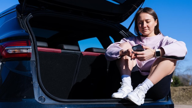 Eine junge Frau im Trainingsanzug sitzt nach einem Outdoor-Workout in einem Auto