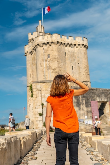 Eine junge Frau im Urlaub neben dem Turm Saint Nicolas von La Rochelle. Küstenstadt im Südwesten Frankreichs