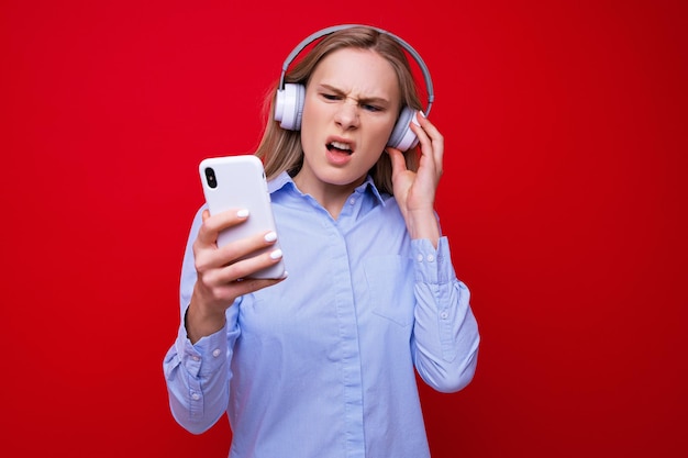 Eine junge Frau in einem Hemd hört Musik von ihrem Telefon
