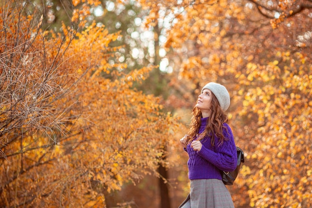 Eine junge Frau in einem Herbstpark in einem lila Pullover