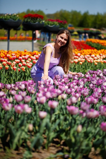 Eine junge Frau in einem rosa Anzug steht in einem blühenden Tulpenfeld. Frühlingszeit