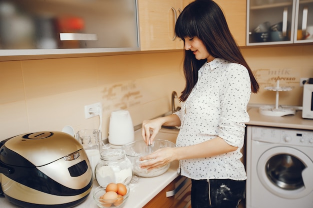 eine junge Frau in einem weißen Hemd bereitet zu Hause Essen in der Küche zu