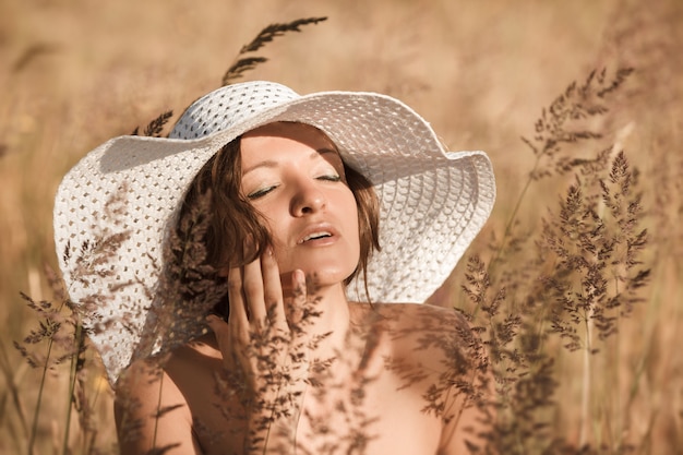 Eine junge Frau in einem weißen Hut genießt die Sonne