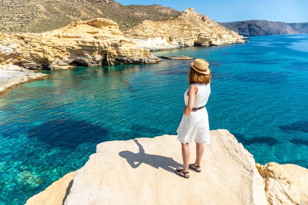 Eine junge Frau in einem weißen Kleid mit Blick auf das Meer in Rodalquilar in Cabo de Gata an einem schönen Sommertag, Almería