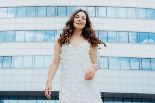 Eine junge Frau in einem weißen Kleid posiert draußen Das Model ist gut gelaunt in der Stadt spazieren