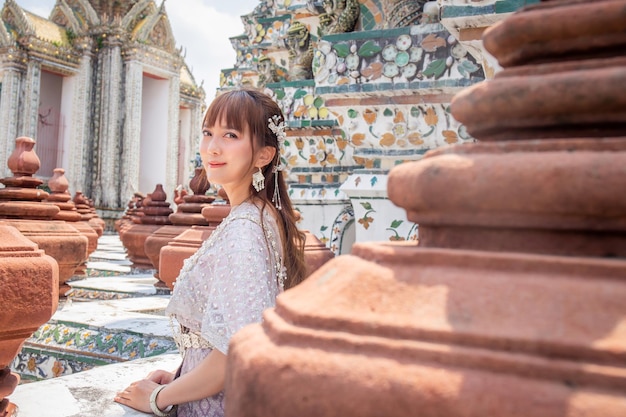 Eine junge Frau in traditioneller thailändischer Kleidung steht in Wat Arun, einem beliebten Reiseziel für Touristen aus der ganzen Welt.