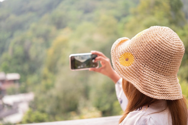 Eine junge Frau kann kein Gesicht in einem Hut sehen, das mit einem Handy spielt