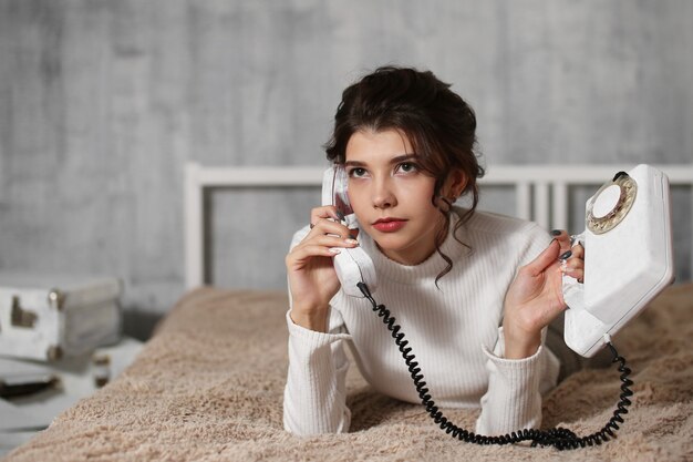 Eine junge Frau liegt in einem Bett und hält ein Telefon