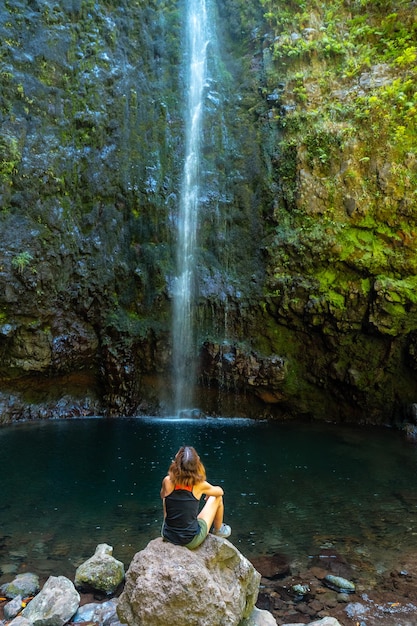 Eine junge Frau mit Blick auf den beeindruckenden Wasserfall an der Levada do Caldeirao Verde Queimadas Madeira