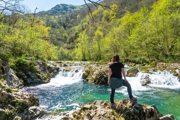 Eine junge Frau mit Blick auf die Wasserfälle am Fluss Sella zwischen El Tornin a la Olla de San Vicente in der Nähe von Cangas de Onis Asturien Spanien