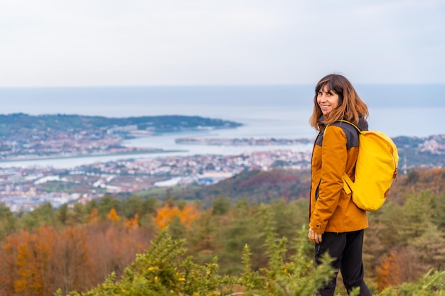 Eine junge Frau mit Blick von der Spitze des Erlaitz über den Fluss Bidasoa und die Gemeinden Fuenterrabia und Hendaya in der Stadt Irun, Gipuzkoa. Baskenland