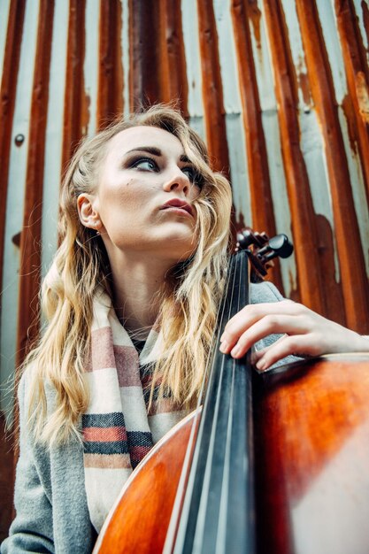 Eine junge Frau mit blonden Haaren hält ein Musikinstrument in einem niedrigen Blickwinkel