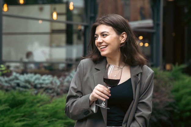 Eine junge Frau mit einem Glas Wein draußen in der Nähe eines Restaurants