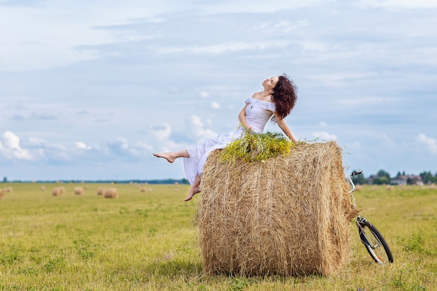 eine junge Frau mit einem großen Blumenstrauß an einem Sommertag auf einem gemähten Feld