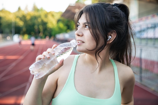 Eine junge Frau mit einer Flasche Wasser im Training im Stadion