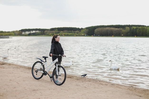 Eine junge Frau mit Fahrrad am See