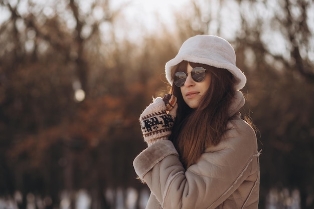 Eine junge Frau mit Hut isst eine Makrone in einem Winterpark