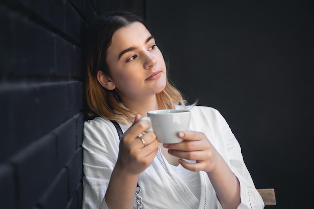 Eine junge Frau mit Kaffeetasse im schwarzen Café-Interieur